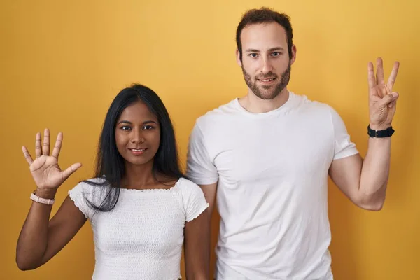 Interracial Couple Standing Yellow Background Showing Pointing Fingers Number Eight — Stock Photo, Image