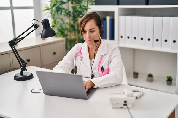 Lekarz Średnim Wieku Kobieta Pracuje Nosząc Słuchawki Myślenia Trzeźwy Wyraz — Zdjęcie stockowe
