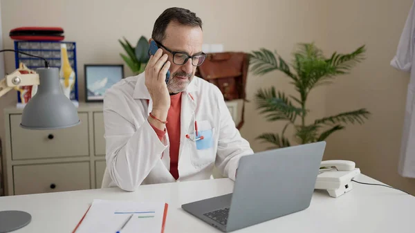 Lekarz Średnim Wieku Pomocą Laptopa Rozmowy Smartfonie Klinice — Zdjęcie stockowe