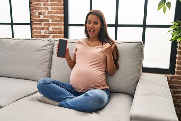 Mladá Těhotná Žena Drží Smartphone Ukazující Ukazující Palec Nahoru Stranu — Stock fotografie