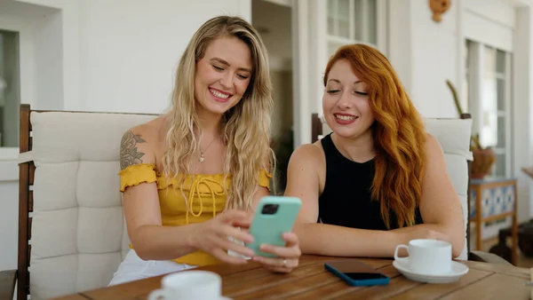Δύο Γυναίκες Που Χρησιμοποιούν Smartphone Και Πίνοντας Καφέ Κάθονται Στο — Φωτογραφία Αρχείου