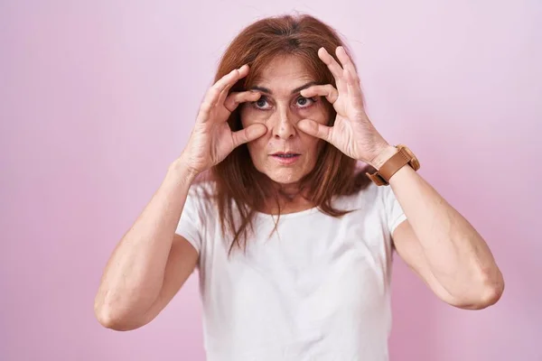 Middle Age Woman Standing Pink Background Trying Open Eyes Fingers — Stockfoto