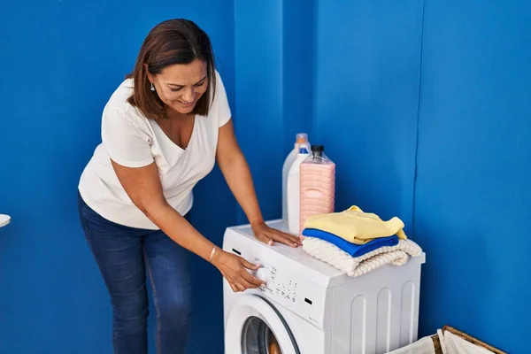 中年惊慌失措的女人带着自信的笑容在洗衣房洗衣服 — 图库照片