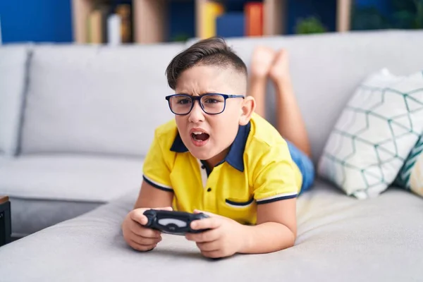 年轻的孩子在沙发上玩电子游戏 手里拿着控制器 怒气冲冲地尖叫着 怒气冲冲地大叫着 愤怒和好斗的概念 — 图库照片