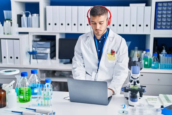 Young Hispanic Man Scientist Using Laptop Headphones Laboratory — ストック写真