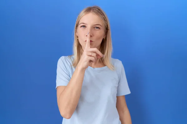 年轻的高加索女人穿着休闲的蓝色T恤 要求保持安静 手指放在嘴唇上 沉默和秘密概念 — 图库照片