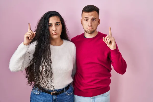 Young Hispanic Couple Standing Pink Background Pointing Looking Sad Upset — Stock Photo, Image