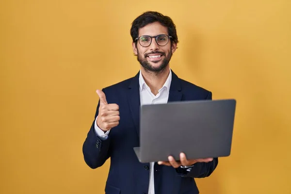 英俊的拉丁男人用电脑笔记本电脑做着快乐的大拇指举手表决姿势 赞成的表情看着相机显示的成功 — 图库照片
