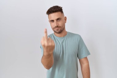 Hispanic man with beard standing over white background showing middle finger, impolite and rude fuck off expression 