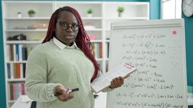 Örgü örmüş saç öğretmeni olan Afrikalı kadın üniversite kütüphanesinde matematik dersi veriyor.
