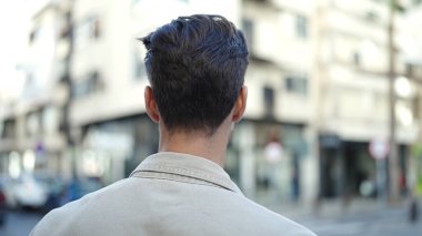 Latin kökenli genç bir adam sokakta dikiliyor.