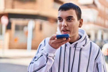 Genç adam gülümsüyor. Kendine güveniyor. Sokakta akıllı telefondan konuşuyor.