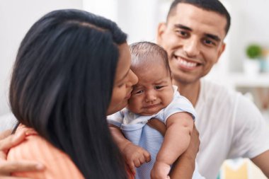İspanyol ailesi evdeki koltukta otururken kendinden emin gülümsüyor.