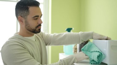 Young hispanic man cleaning toaster at home