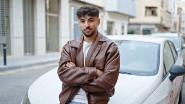 Arabasının yanında duran genç bir Arap caddede çapraz hareketler yapıyor.