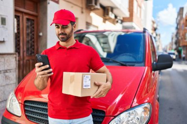 Genç İspanyol kurye sokakta akıllı telefon paketi kullanıyor.