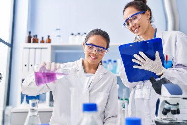 Woman and girl wearing scientist uniform working at laboratory