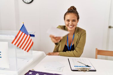 Young beautiful hispanic woman electoral table president holding vote at electoral college