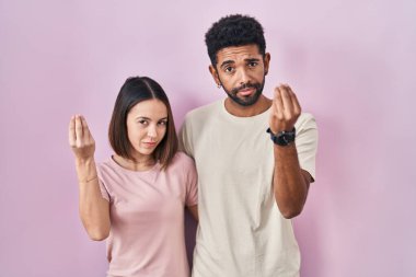 Pembe arka planda genç bir İspanyol çift el ve parmakları ile italyan jestleri yapıyor. 
