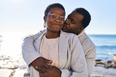 Erkek ve kadın çift sahilde birbirlerine sarılıyorlar.