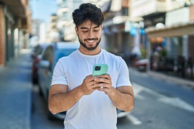 Sokakta akıllı telefon kullanan, kendine güvenen genç bir İspanyol.