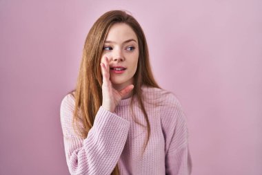 Pembe arka planda duran beyaz bir kadın. Ağız üstünde el ele. Gizli dedikodular, kötü niyetli konuşmalar. 