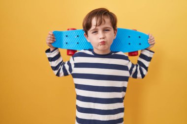 Sarı arka planda paten kayan beyaz bir çocuk öpüşürken kameraya bakıyor. Güzel ve seksi. aşk ifadesi. 