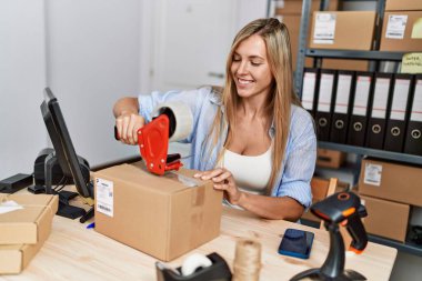 Genç sarışın kadın ecommerce iş işçisi ofiste paket paketleme