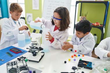 Bir grup öğrenci laboratuvar sınıfında deney yaparak şişenin üzerine sıvı döküyorlar.