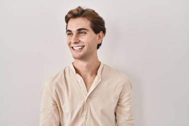 İzole edilmiş arka planda duran genç adam yüzünde gülümseme ve doğal ifadeyle yan yana bakıyor. Kendinden emin gülen. 