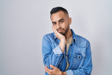 Tecrit edilmiş arka planda duran genç İspanyol adam çapraz kollarla depresyon sorunlarından sıkılmış ve yorgun göründüğünü düşünüyor.. 