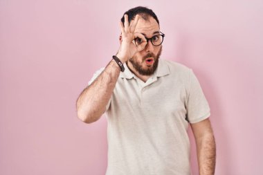 Artı, pembe arka planda sakallı İspanyol bir adam. Şaşırmış yüz ifadesiyle şaşırmış, parmaklarından bakan bir jest yapıyor. İnançsız ifade. 