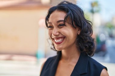 Young beautiful hispanic woman smiling confident looking to the side at street