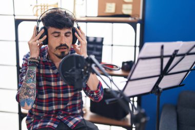 Young hispanic man artist singing song at music studio