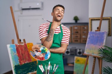 Brezilyalı genç bir adam ressam stüdyosunda paleti tutuyor. Gülmekten kırılıyor, kahkahalarla gülüyor.. 