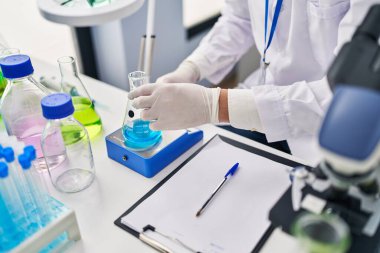 Genç İspanyol bilim adamı laboratuvarda sıvı yazım raporunu ölçüyor.