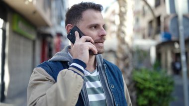 Young caucasian man speaking on the phone at street