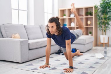 Young hispanic man training yoga at home