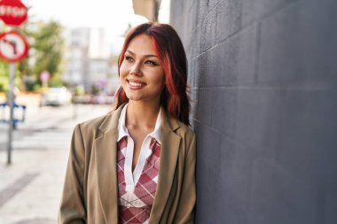 Beyaz kadın gülümsüyor. Kendinden emin. Caddenin kenarına bakıyor.