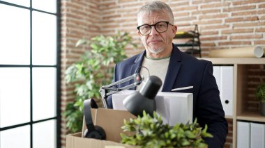 Middle age grey-haired man business worker dismissed holding cardboard box at office clipart