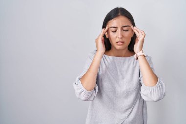 Young hispanic woman standing over white background with hand on head, headache because stress. suffering migraine. 