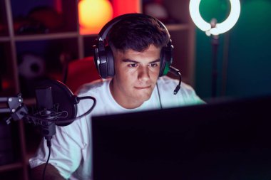 Oyun odasında bilgisayar kullanarak video oyunu oynayan İspanyol asıllı genç adam.