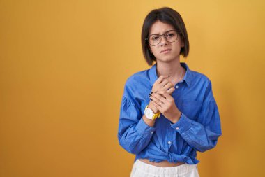 Sarı arka planda duran genç kız ellerinde ve parmaklarında ağrı, eklem iltihabı. 