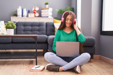 Genç ve güzel İspanyol kadın evde oturmuş müzik dinliyor.