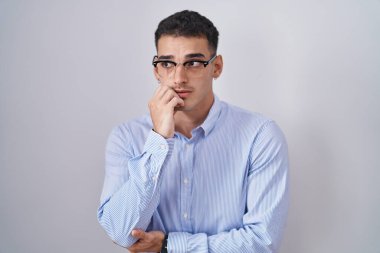 İş kıyafetleri ve gözlük takan yakışıklı, gergin ve ağzı tırnak yiyen elleri olan bir İspanyol. anksiyete. 