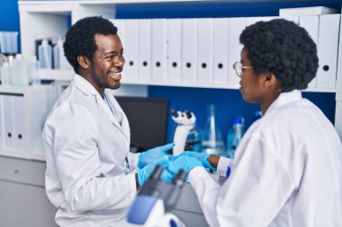 Afrika kökenli Amerikalı erkek ve kadın bilim adamları laboratuarda birlikte çalışıyorlar.