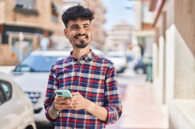 Sokakta akıllı telefon kullanan, kendine güvenen genç bir İspanyol.