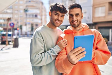 İki erkek caddede birbirlerine dokunarak sarılıyorlar.