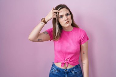 Pembe arka planda duran sarışın beyaz kadın alnındaki sivilceden mutsuz olduğunu gösteriyor. Siyah noktalı çirkin bir enfeksiyon. sivilce ve deri problemi 