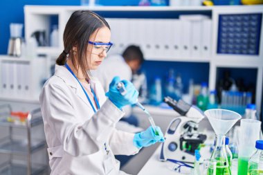 Man and woman scientists pouring liquid on test tube at laboratory